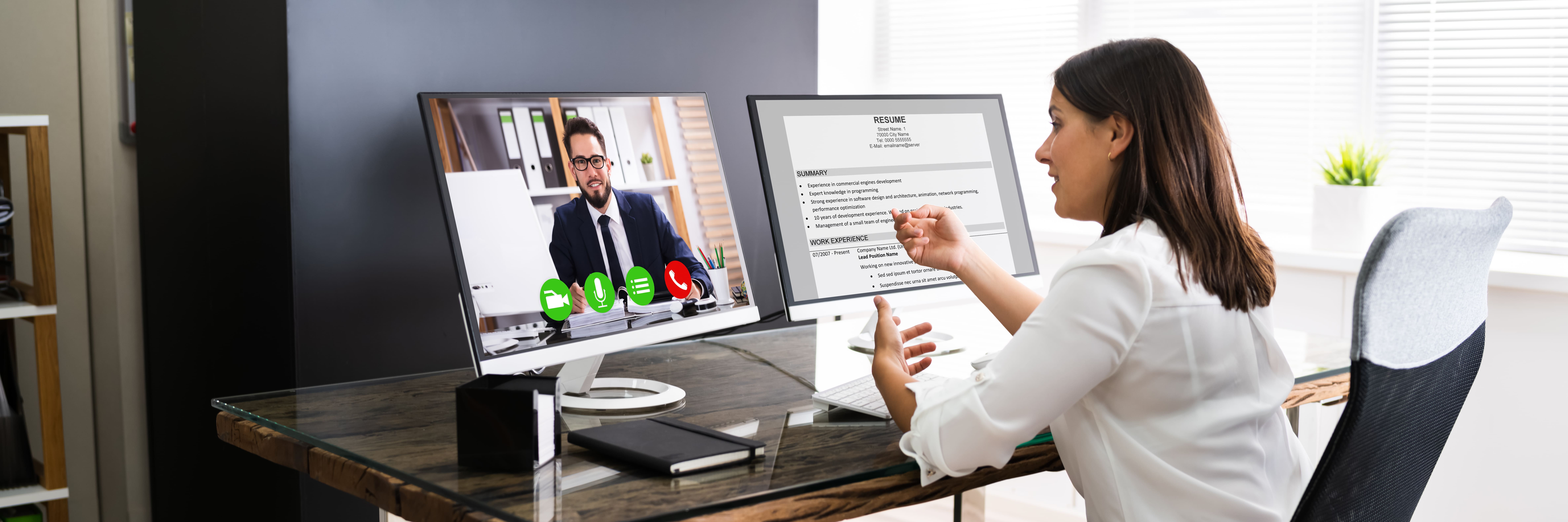 Woman at desk with dual monitors conducting online interview, focused on recruitment support for Fluid Resourcing hiring process