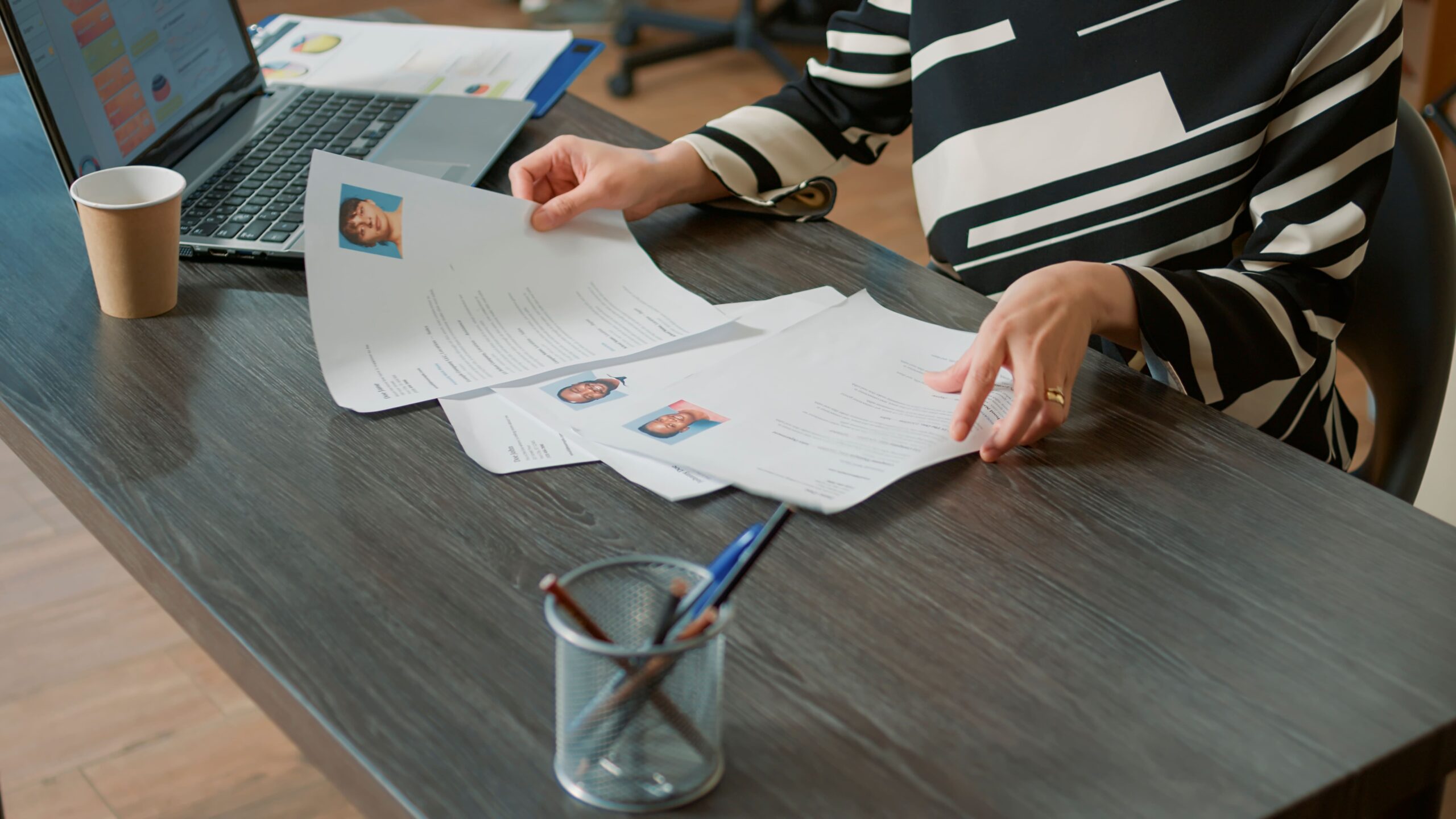 Woman seated at desk using laptop with documents, preparing reports for Fluid Resourcing workforce planning and operations support