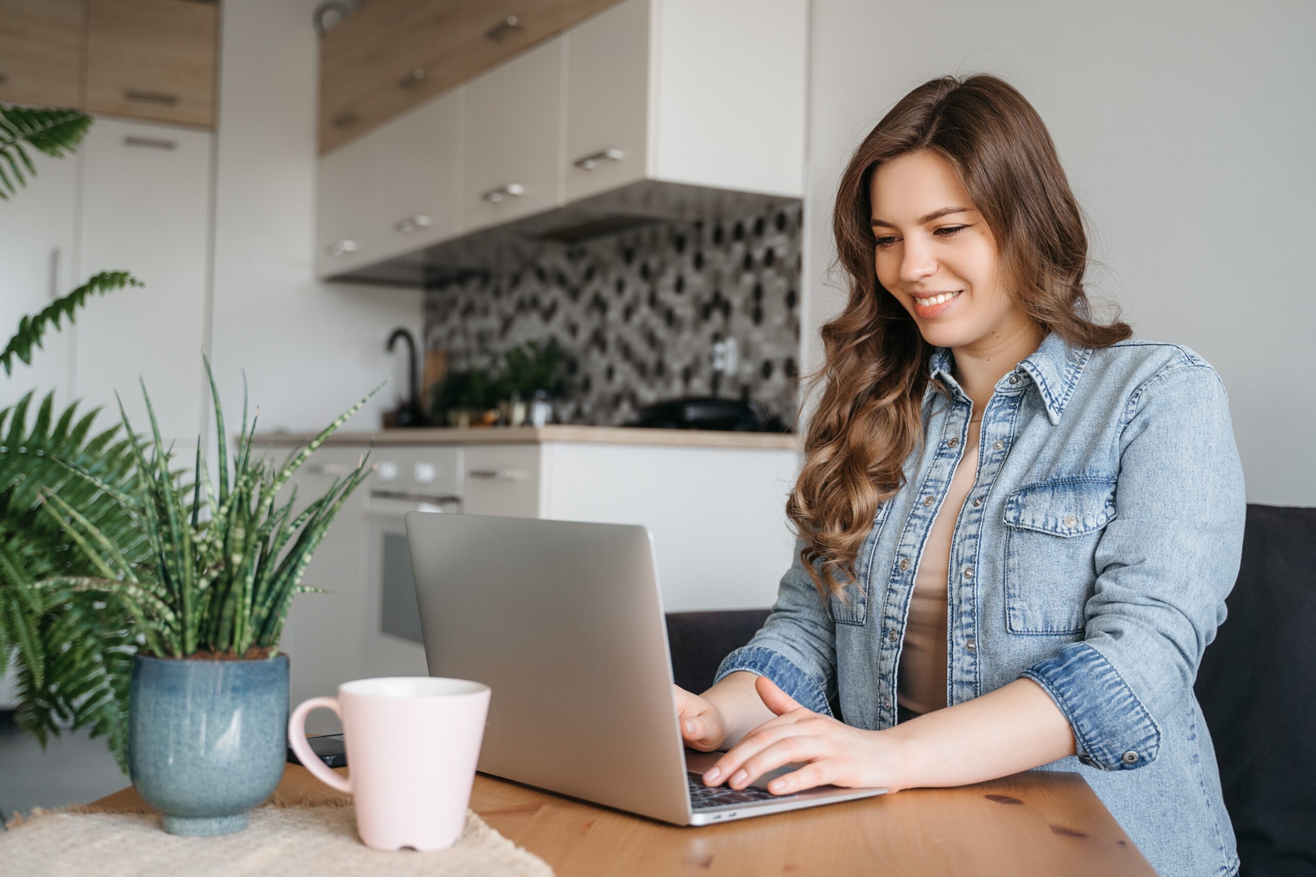 Smiling woman working on a laptop in a home office, reflecting flexible remote opportunities with Fluid Resourcing services