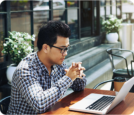 A man focused on his laptop in a cafe, representing Fluid Resourcing and the use of virtual talent for productivity