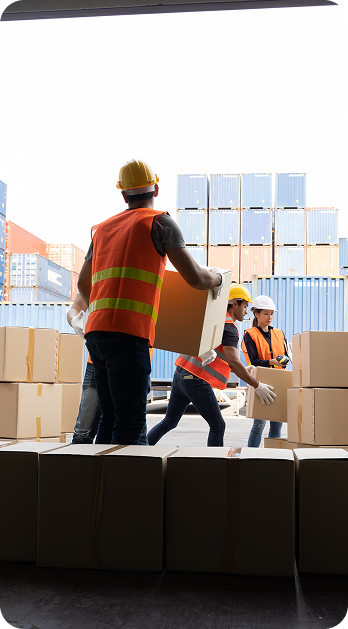 Three workers in safety vests and hard hats carry boxes on-site, supporting logistics and supply chain operations by Fluid Resourcing