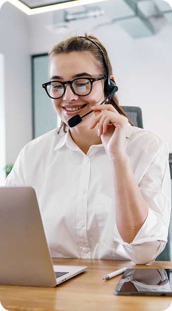 A woman wearing glasses and a headset works at a desk with a laptop, illustrating Fluid Resourcing for staffing in business services