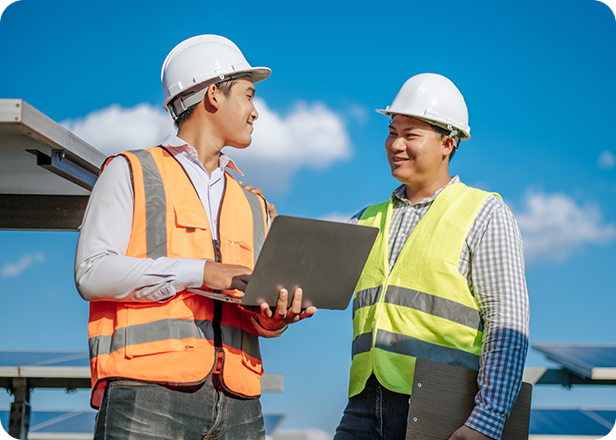 Two men in hard hats and safety vests using laptops on a work site, representing Fluid Resourcing for in-person relocations workforce solutions